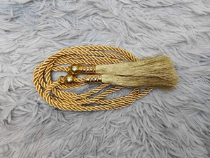 Detailaufnahme einer goldenen geflochtenen Taillenkordel mit Quasten für Damenkleider