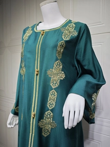 Détail de broderie géométrique dorée et boutons boules sur robe caftan vert foncé