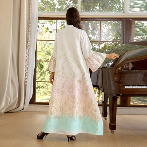 Elegant white gradient maxi robe with floral embroidery and ruffle sleeves on piano
