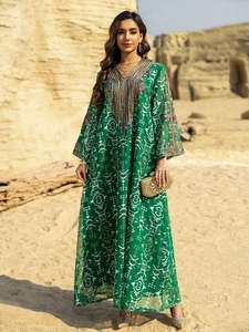 Détail d'une robe maxi bohème verte avec broderies complexes et glands colorés