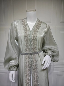 Detail of sage green kaftan with silver leaf embroidery and balloon sleeve accents
