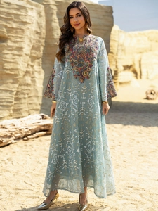 Close-up of intricate heavy embroidery and geometric patterns on a blue kaftan dress