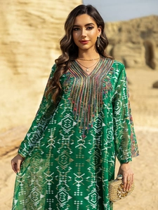 Détail de robe caftan vert émeraude avec broderie blanche et décolleté perlé raffiné