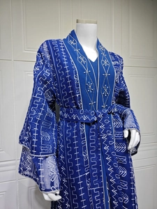 Détail d'une robe bleu foncé avec broderie géométrique blanche et poignets perlés à la main