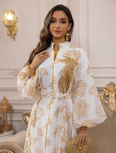 Detail of white Jalabiya dress featuring gold leaf embroidery and lantern sleeves