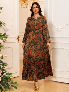 Detailed view of the gold wavy neckline trim on a dark green floral printed long dress