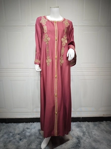 Détails de broderies géométriques dorées et boutons traditionnels sur abaya bordeaux