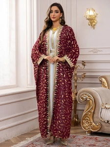 Détail d'un caftan en mousseline bordeaux avec imprimés plumes dorées et franges élégantes