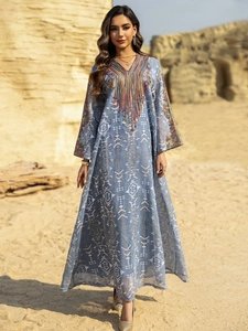 Détail de l'encolure brodée et des glands sur la robe longue bohème en tulle bleu