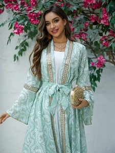 Dettaglio dell'abaya verde menta ricamata con motivi floreali e bordo di paillettes dorate