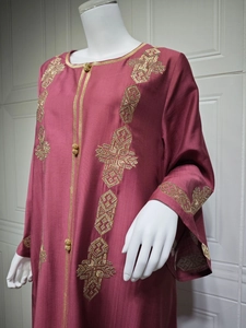 Détails de broderie géométrique dorée sur les manches et l'avant de la robe longue