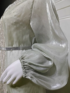 Detail of elegant light green dress featuring shimmering rhinestones and puffed lantern sleeves