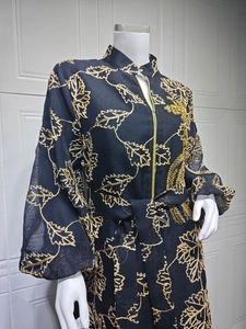 Detail of Jalabiya dress featuring gold leaf embroidery and zip closure on black fabric