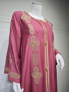 Détails de broderie dorée et boutons décoratifs sur une robe caftan de couleur magenta