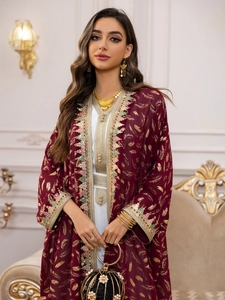 Détails de l'imprimé plume dorée sur robe en mousseline bordeaux avec broderies de luxe