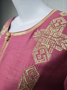 Détail de la broderie géométrique dorée et paillettes argentées sur robe rose ethnique