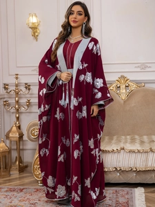 Détails de broderie florale argentée et de franges sur cette robe caftan rouge foncé