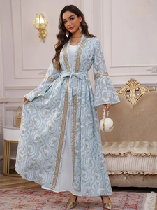Dettaglio dell'abaya ricamata azzurro con bordo dorato e motivi floreali bianchi fini