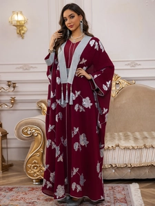 Détail d'une abaya bordeaux avec broderie florale argentée et élégants glands longs