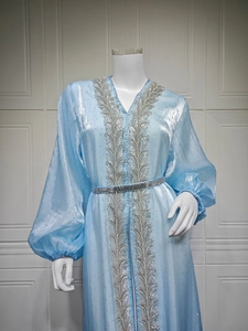 Detailed close-up of light blue kaftan with silver leaf embroidery and sparkly fabric