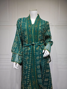 Détail d'un caftan vert émeraude avec broderies dorées et motifs perlés complexes