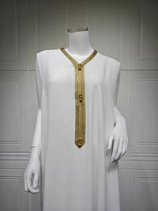 Détail de robe longue blanche avec broderie dorée et perles de style ethnique