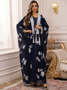 Détail de broderie florale argentée et longues franges sur tissu Abaya bleu foncé