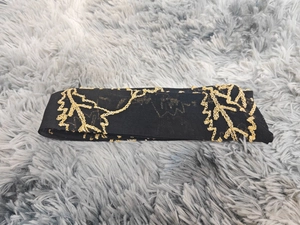 Detailed close-up of black tulle fabric with gold sequin floral embroidery and branch motifs