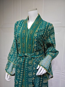Détail du caftan vert avec broderies dorées, col en V, manches cloche et ceinture