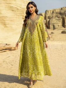 Détail de broderie multicolore et perles sur une robe caftan en maille verte