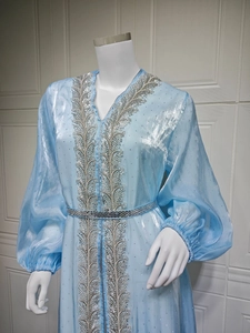Detail of light blue kaftan featuring silver feather embroidery and rhinestone belt