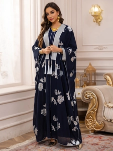 Détails de broderies florales argentées et de pompons sur une robe abaya bleu marine