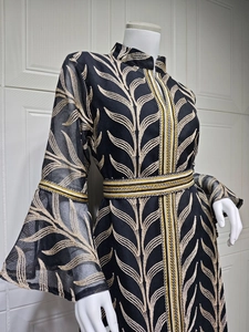 Macro shot of gold leaf embroidery on black kaftan dress with trumpet sleeves