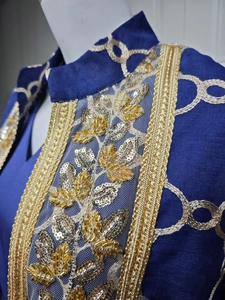Detail eines marineblauen Leinenkleids mit goldenen Pailletten und Blattstickerei-Verzierung