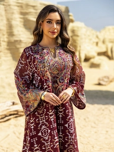 Close-up of intricate colorful embroidery and sequins on a deep red mesh maxi dress
