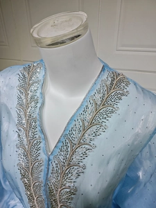 Close-up of light blue V-neck cardigan featuring intricate silver beadwork and sequins