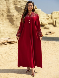 Detail of floral embroidery on a burgundy long-sleeved dress with gold buttons