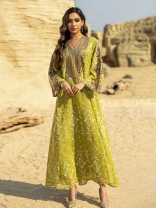 Détails de broderies ethniques et motifs blancs sur la robe longue maxi de couleur vert jaune