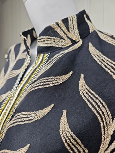 Detail of elegant black embroidery dress featuring golden floral patterns on bell sleeves