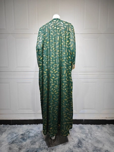 Détail de l'imprimé plume dorée sur une robe longue en mousseline vert foncé pour femme