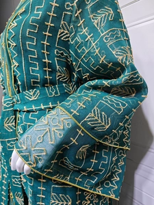 Gros plan détaillé de la robe en tulle vert foncé avec broderies et paillettes dorées