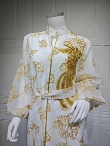 Close-up of golden leaf embroidery and intricate beadwork on a white jalabiya dress