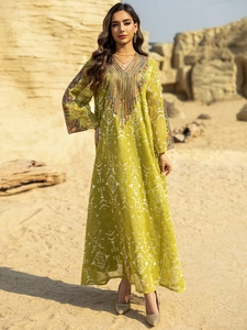 Détail du décolleté brodé et des glands sur robe de soirée longue vert citron en tulle