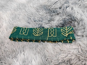 Détail de la broderie de robe en tulle vert foncé avec motifs de feuilles dorées et texture