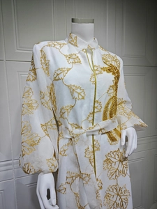Detail of white Jalabiya dress featuring gold leaf embroidery and lantern sleeves