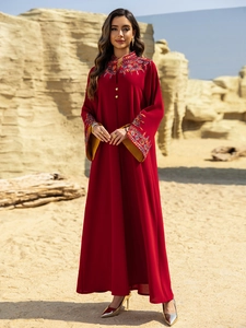 Close-up of ethnic embroidery on neckline and bell sleeves of a red abaya dress