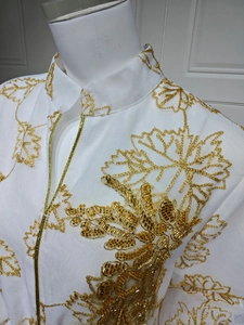 Detail of white Jalabiya dress featuring intricate gold floral embroidery and hand-beaded sequins