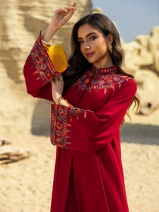 Detailed view of dark red abaya sleeve featuring vibrant floral embroidery and yellow lining