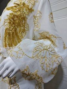 Detail of white kaftan with gold leaf embroidery and intricate beaded embellishments