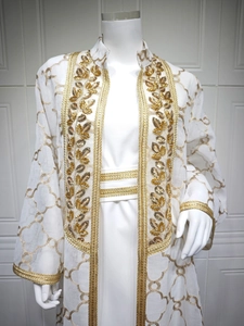 Detail der weißen Abaya mit Goldblattstickerei und Paillettenbesatz auf dem Cardigan